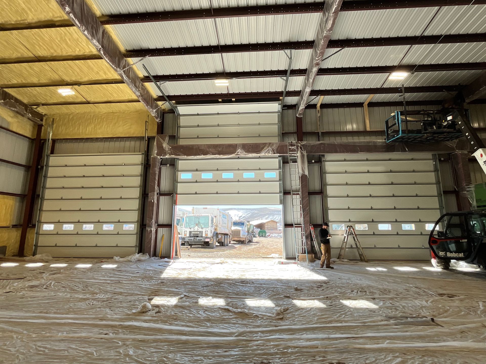 A garage with a black garage door and a brick wall.