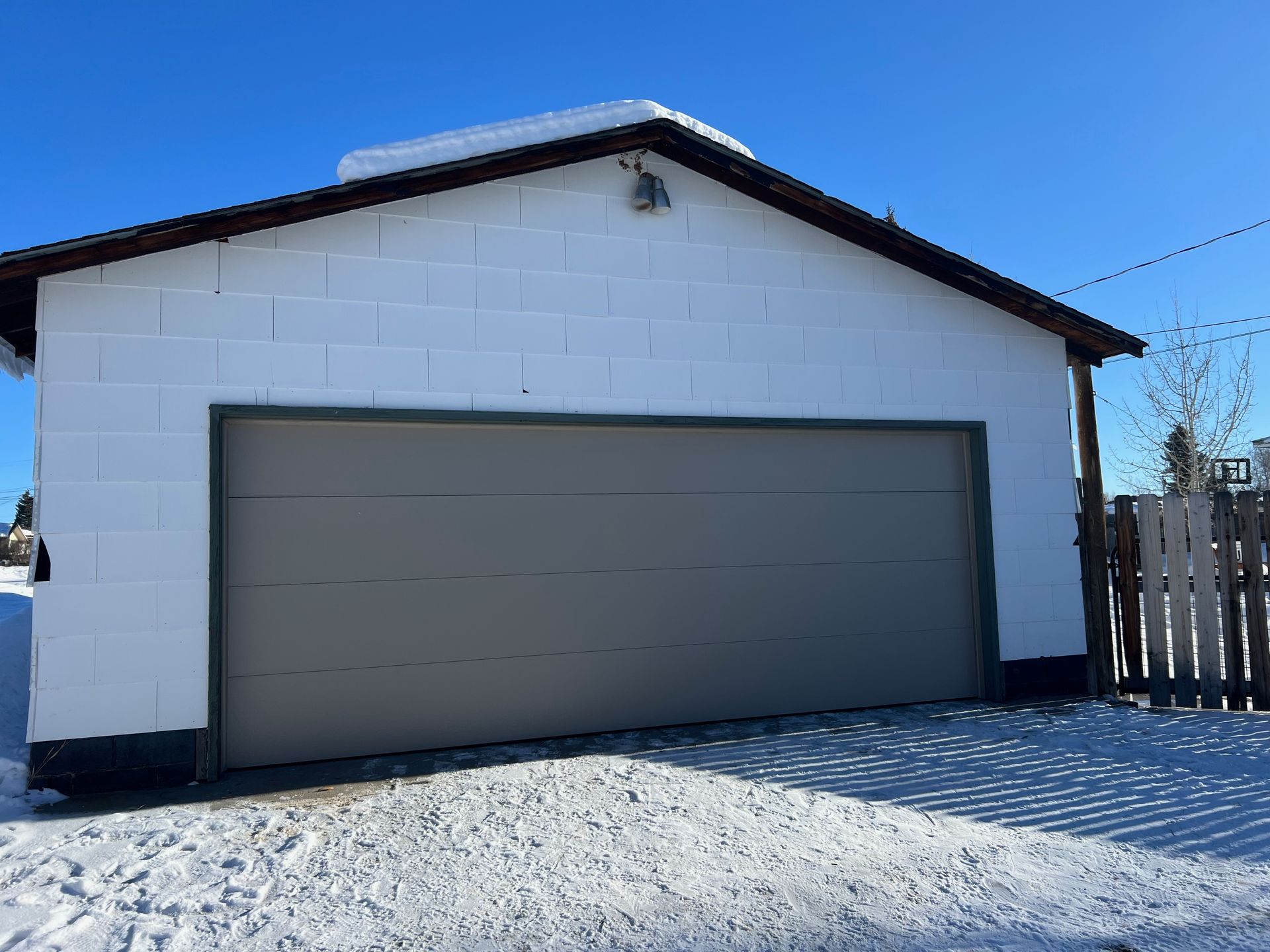A wooden garage door is sitting in front of a black building.