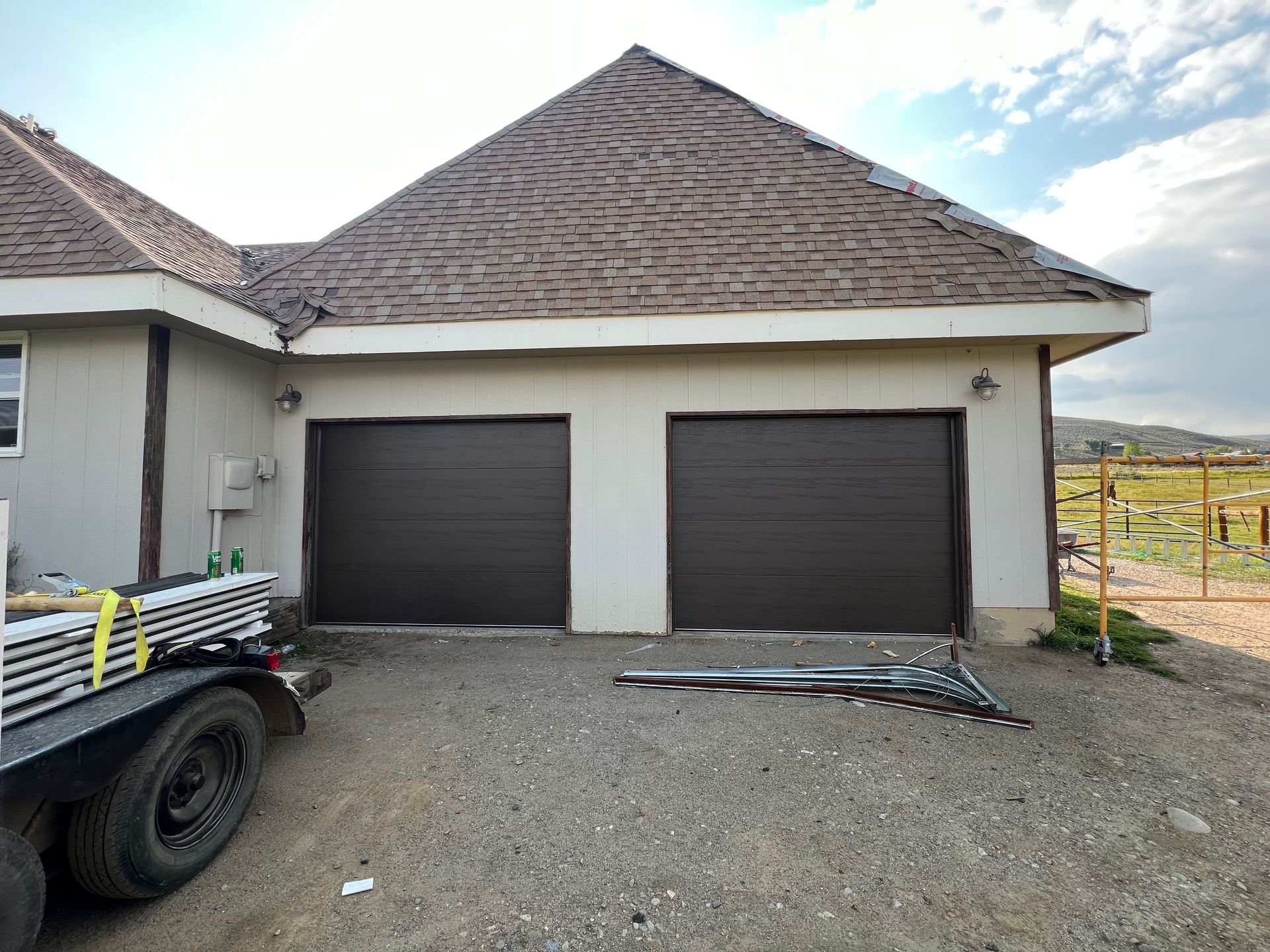A truck is parked in front of a house with two garage doors.