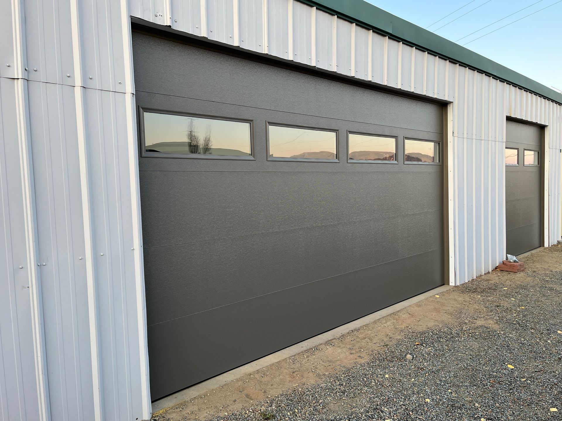 A white building with a gray garage door and windows.