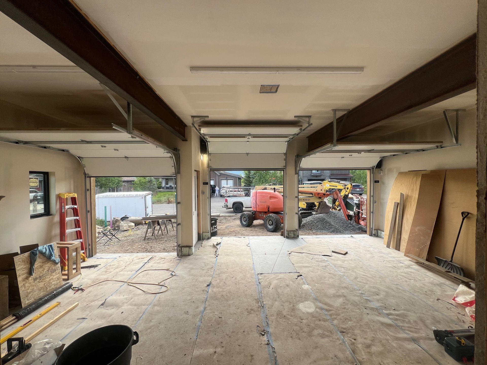 Interior view of a building undergoing renovation. The space is open, with exposed beams, and debris scattered throughout, showing construction work in progress.