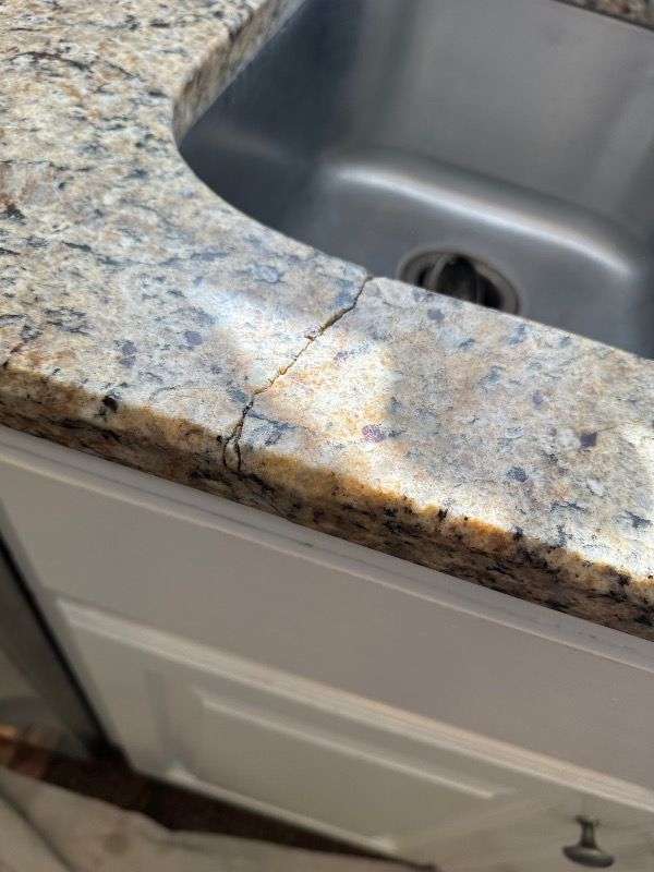 a kitchen sink with a cracked granite counter top .