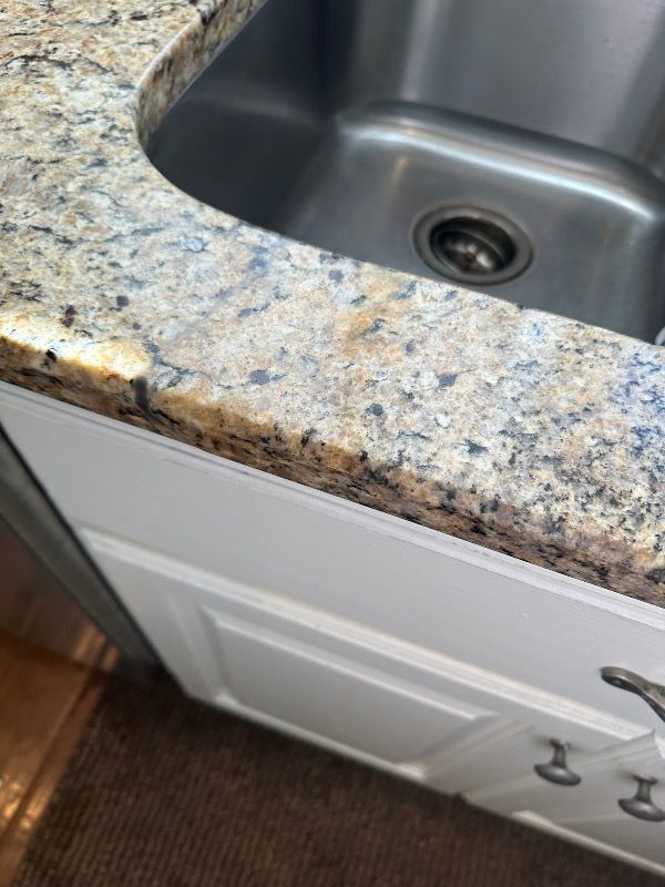 a kitchen sink with a fixed and seamless granite counter top .