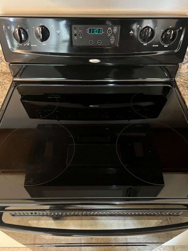 a clean black stove top oven is sitting on top of a granite counter .