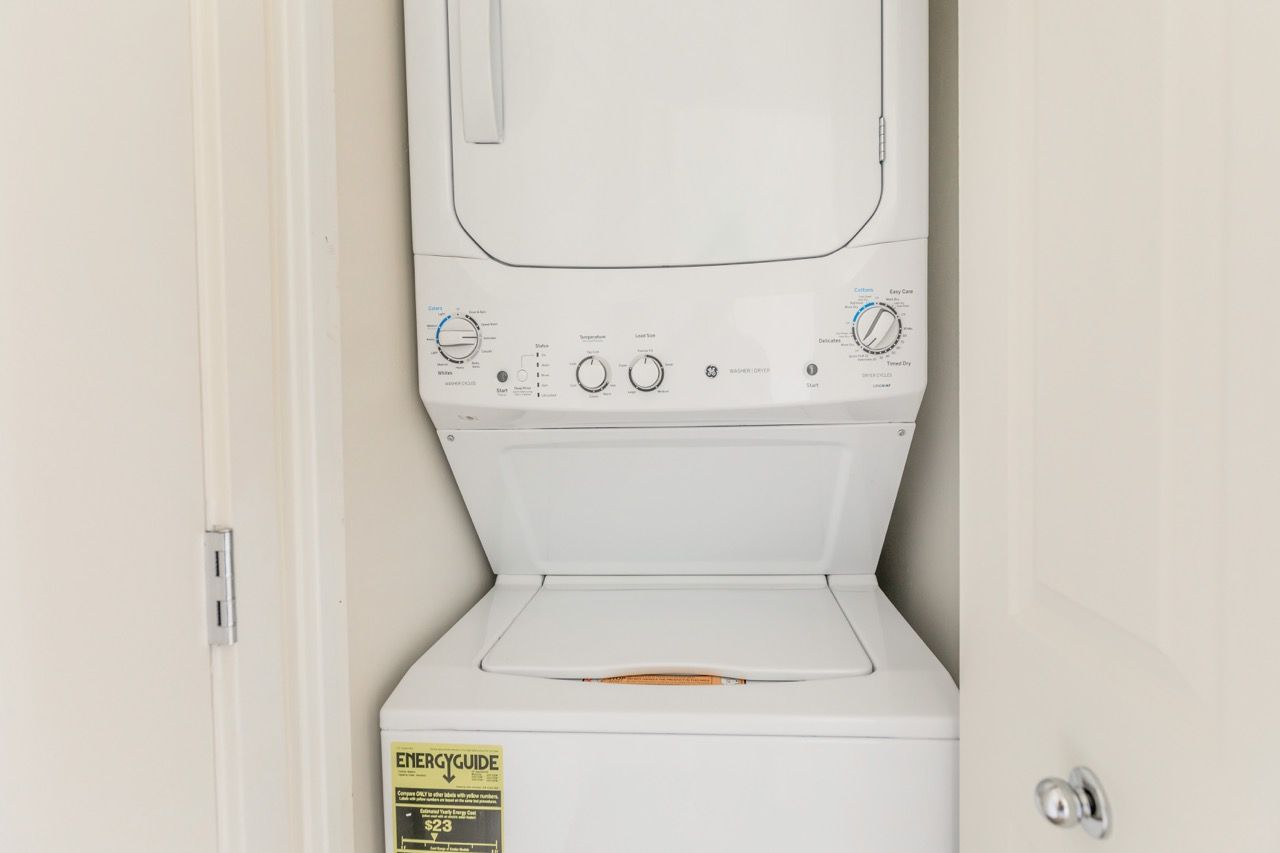 Stacked white washer and dryer in a laundry closet.