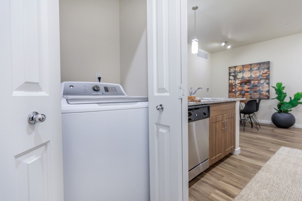Open laundry closet with a washer next to a kitchen island in a modern apartment.