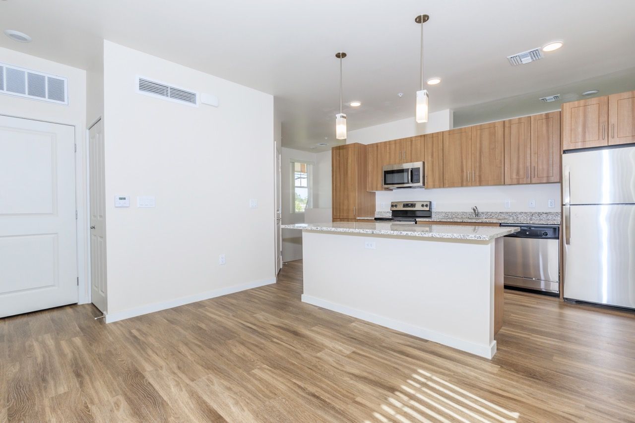 Open kitchen with island, granite counters, stainless steel appliances, and wood cabinets.