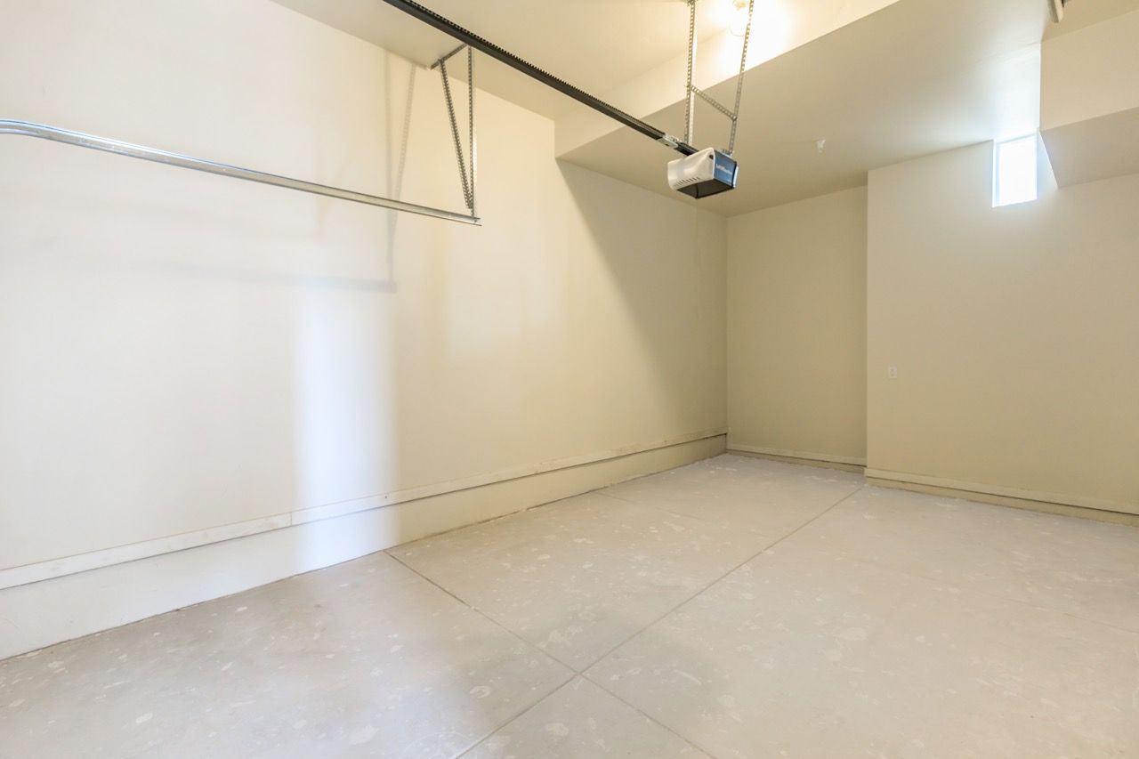 Empty residential garage with a concrete floor and ceiling-mounted garage door opener.