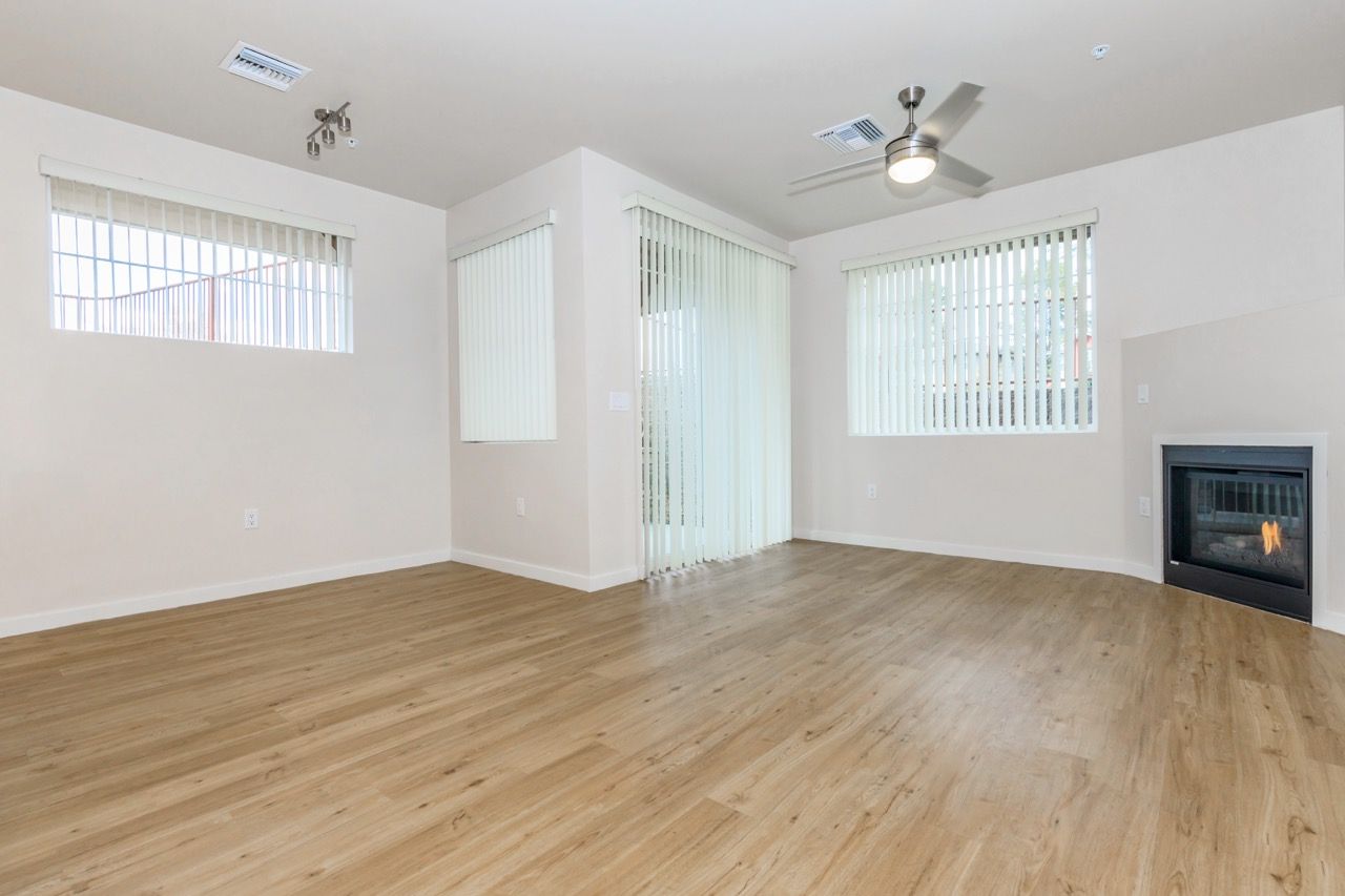 Bright living room with wood-look flooring, fireplace, and vertical blinds.