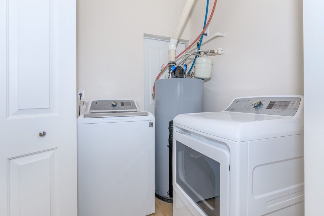 In-unit laundry room with a washer and a dryer beside a water heater.