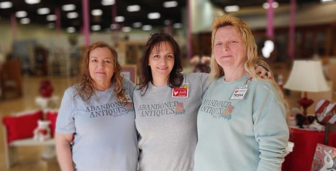 Three women are posing for a picture in a store.