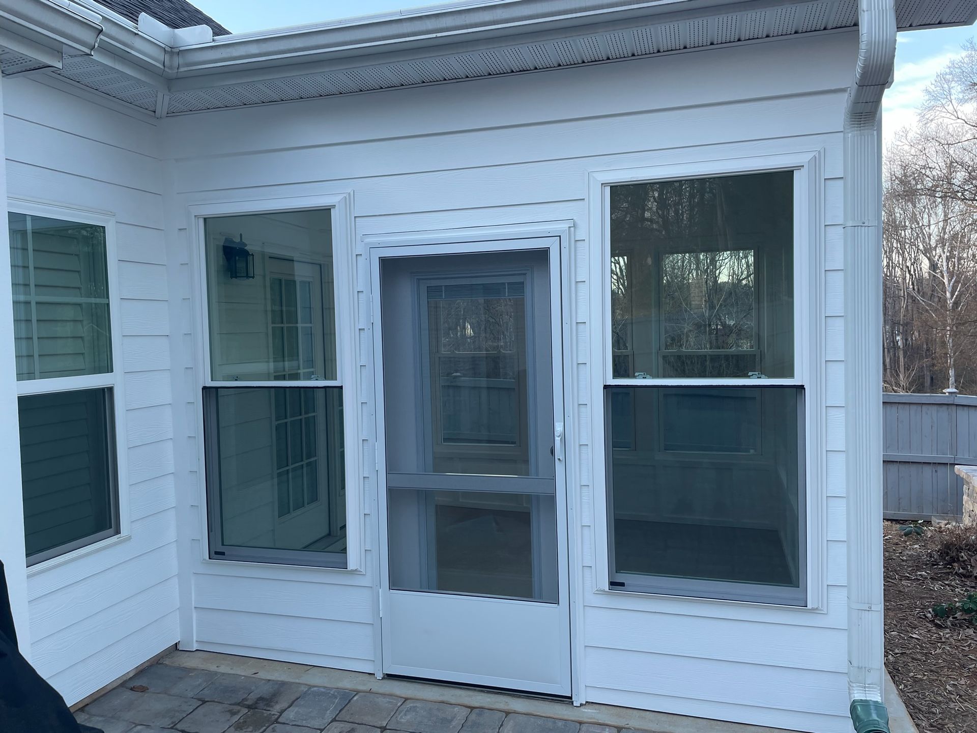 White screened porch on a house with multiple windows and a central screen door