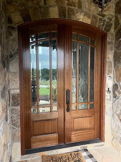 Wooden double front doors with glass panes set in a stone entryway