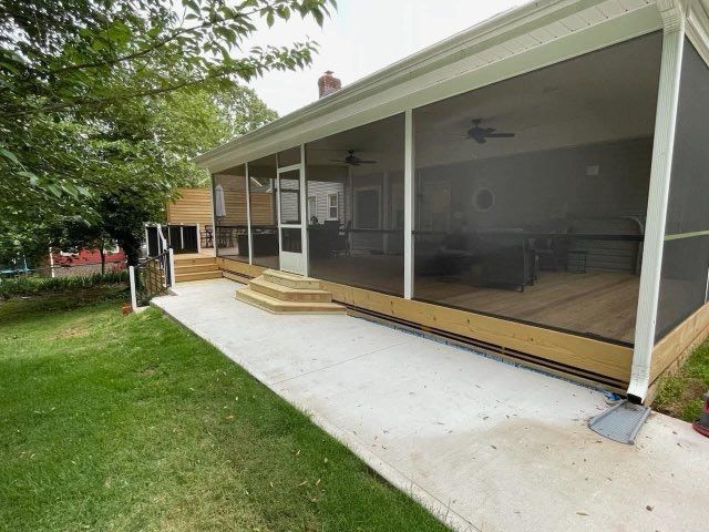 Screened porch with steps and white concrete patio beside a grassy yard