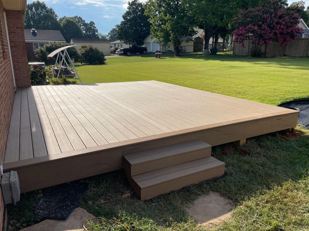 Backyard wooden deck with small steps leading to a grassy yard