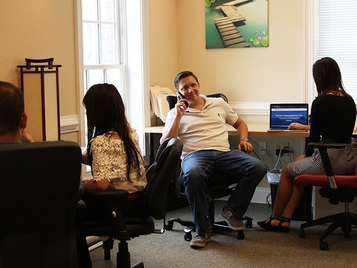 A man is sitting in a chair talking on a cell phone