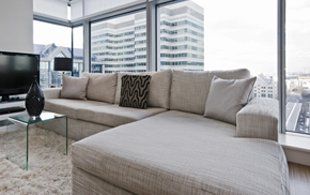 grey sofa in a high rise flat with large window looking out onto buildings