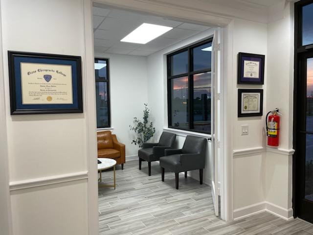 Bright, empty waiting room with seating, diplomas on the wall, and a fire extinguisher.