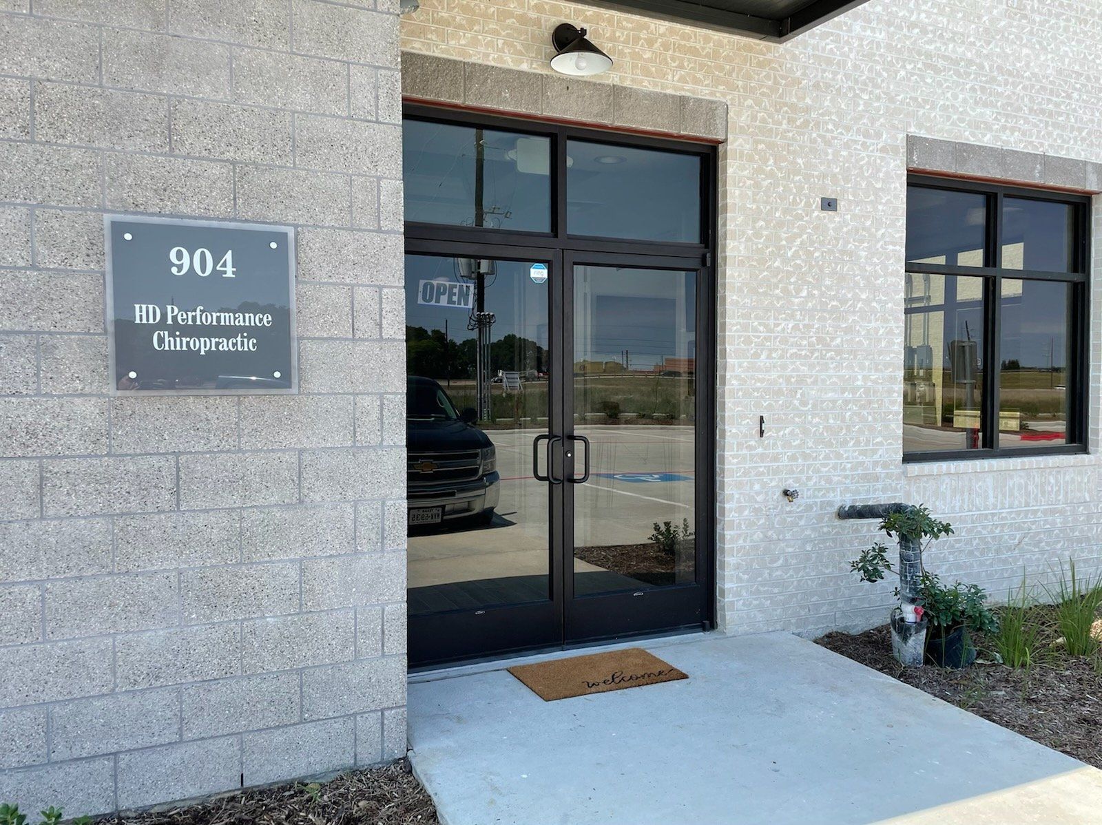 Exterior of chiropractic building with address 904, double doors, and a welcome mat.