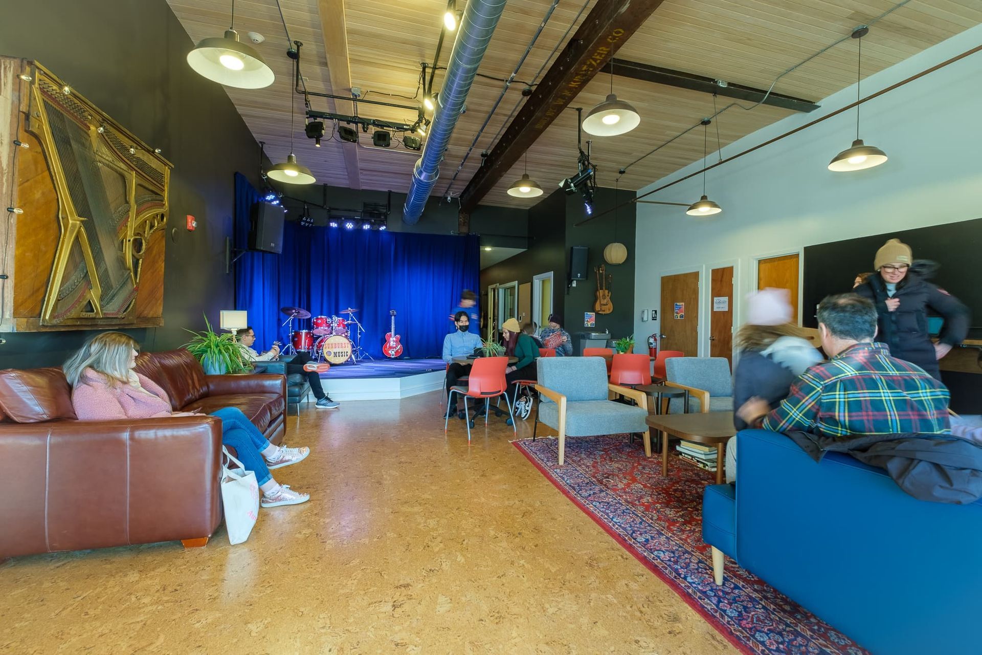 A group of people are sitting in a living room in front of a stage.