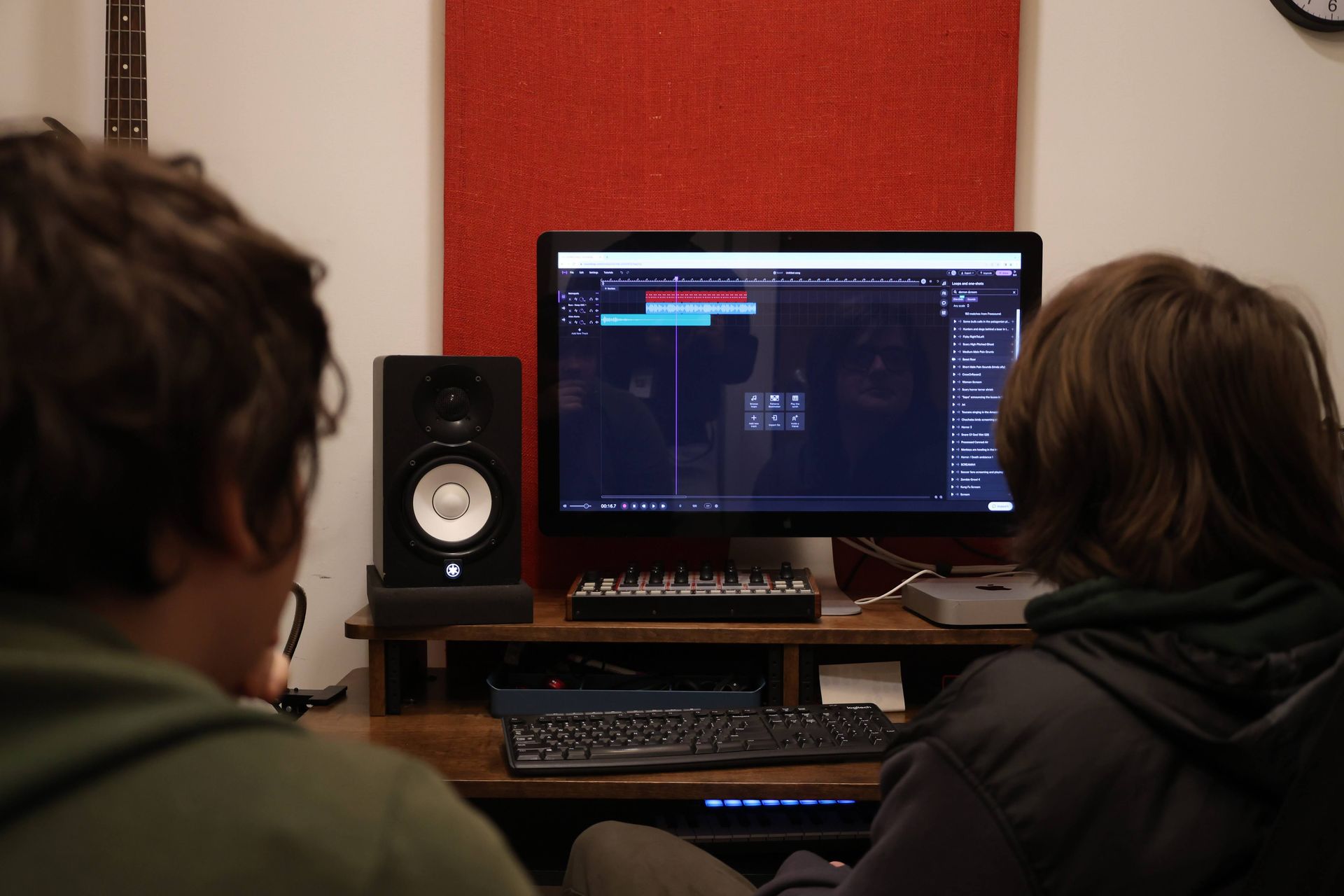 Two people are sitting in front of a computer monitor