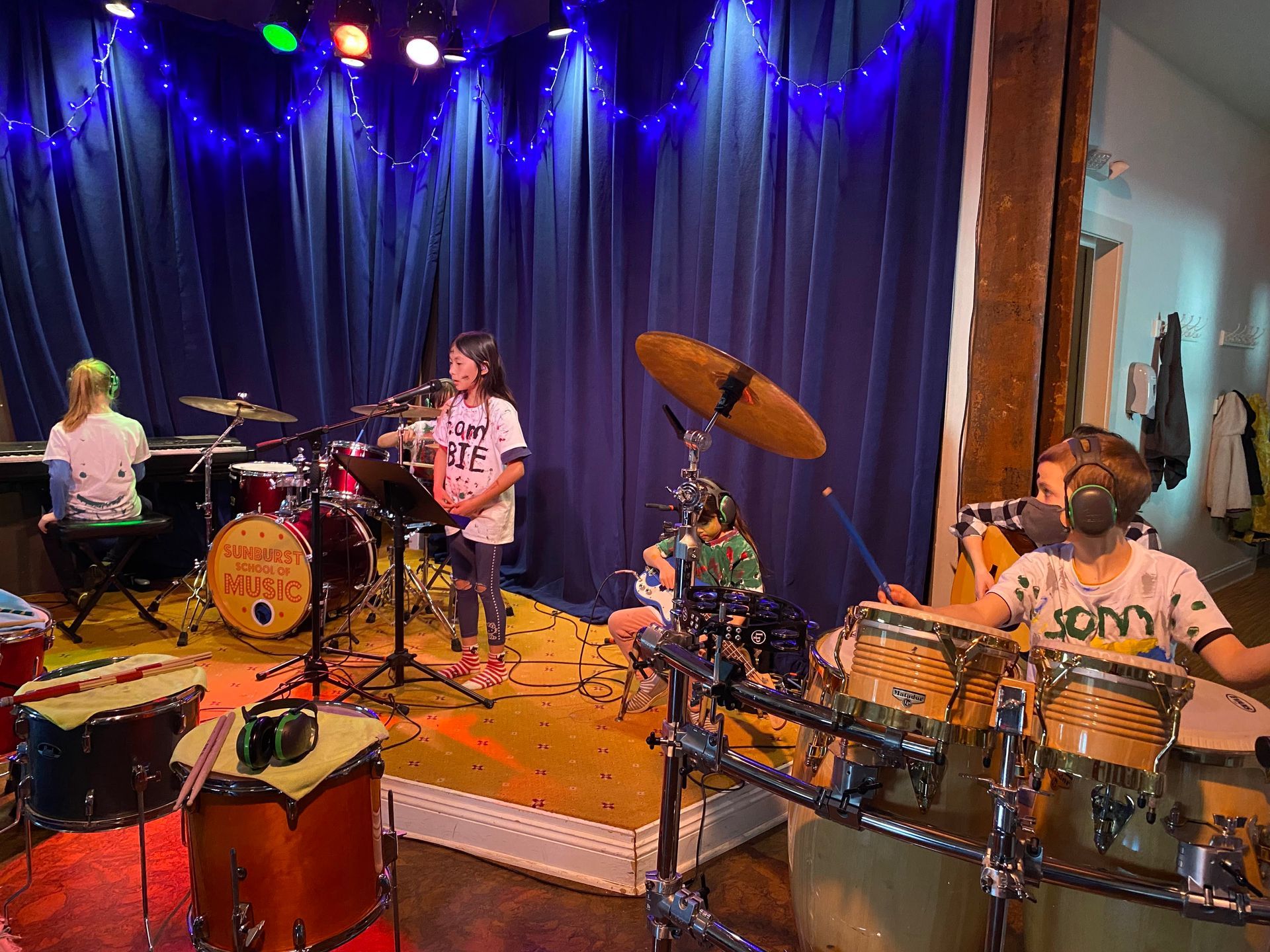 A group of young people are playing drums on a stage.
