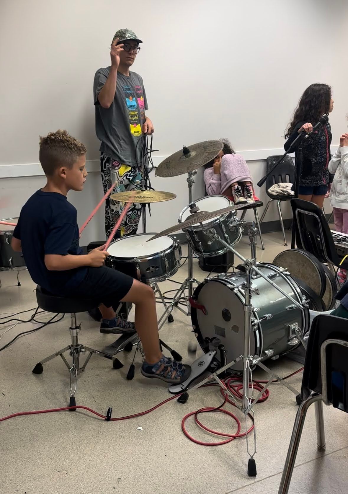 A group of children are playing drums in a room.