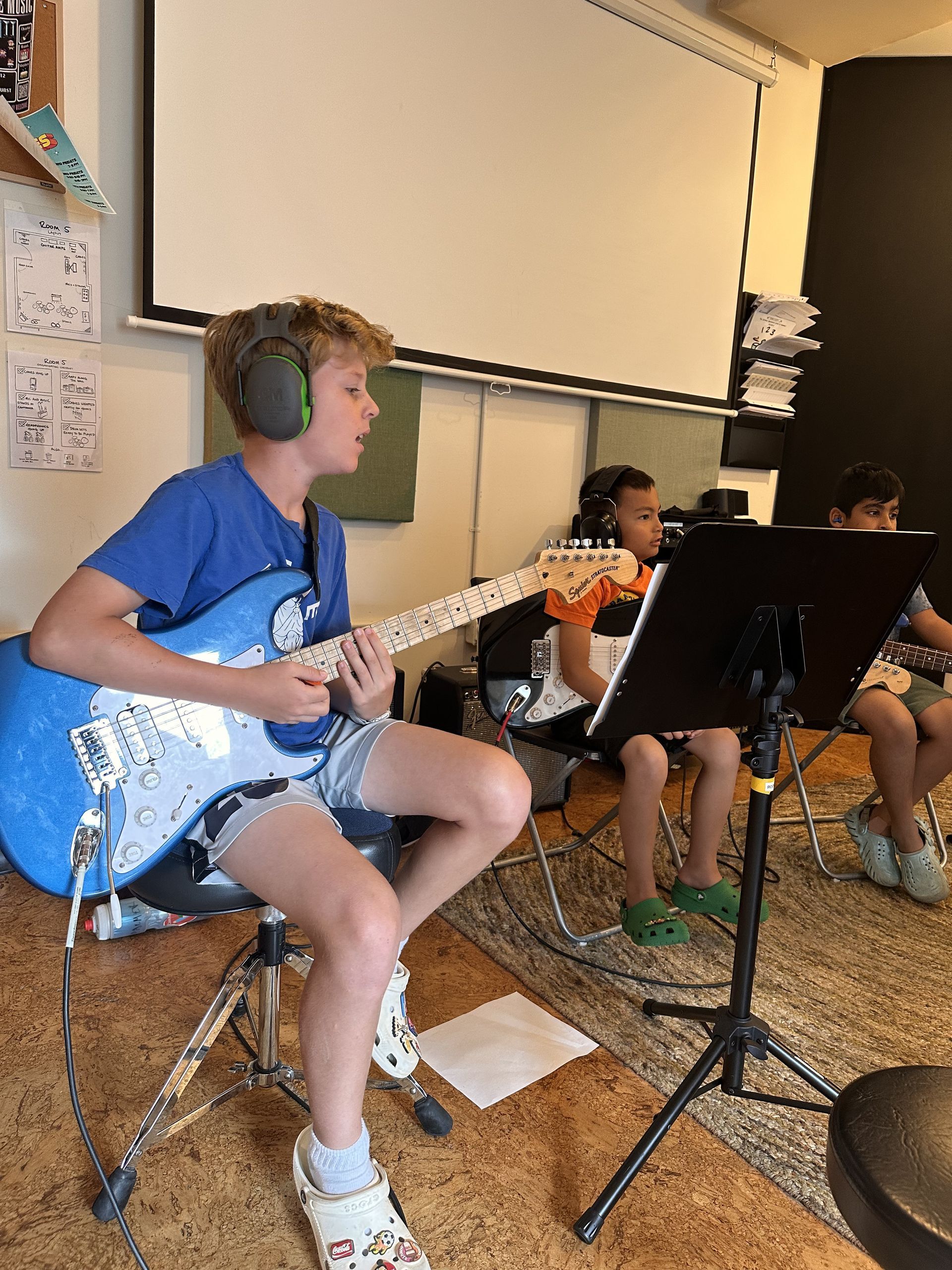 A man wearing a nirvana hoodie is standing next to two other people in a room.