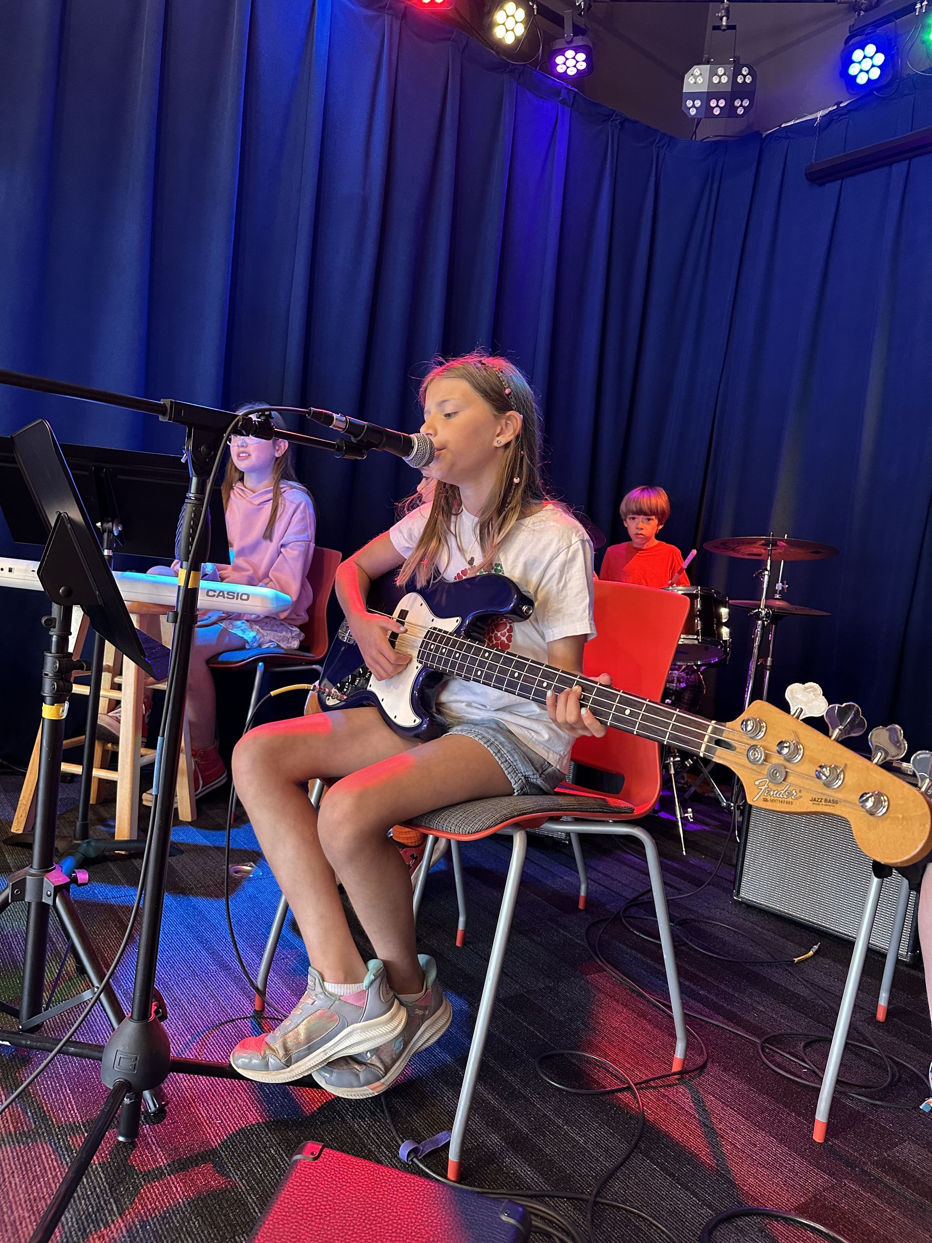 A group of people are standing on a stage playing instruments and singing into microphones.