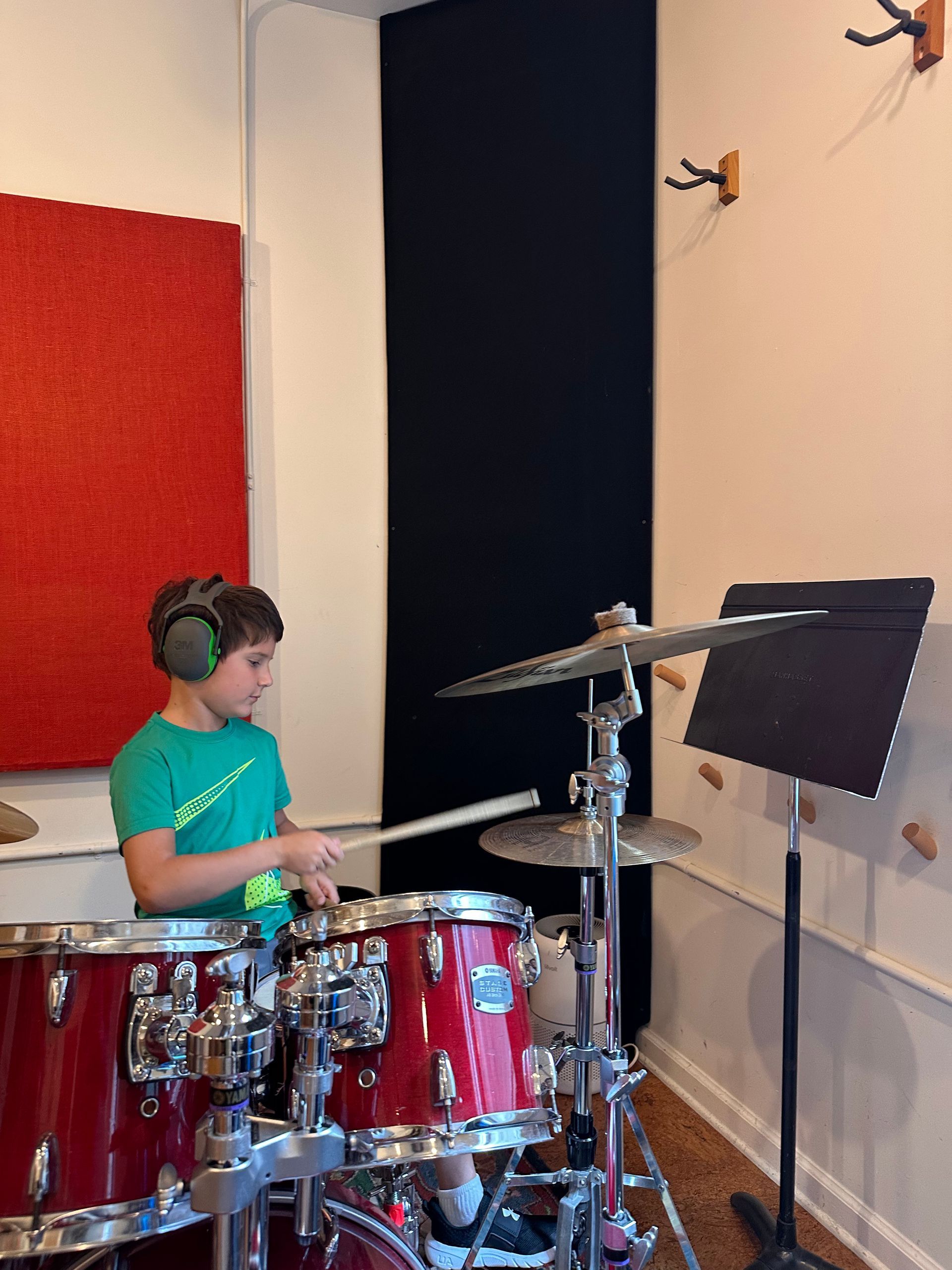 A group of people standing in front of a drum set with one wearing a yellow aero ny shirt