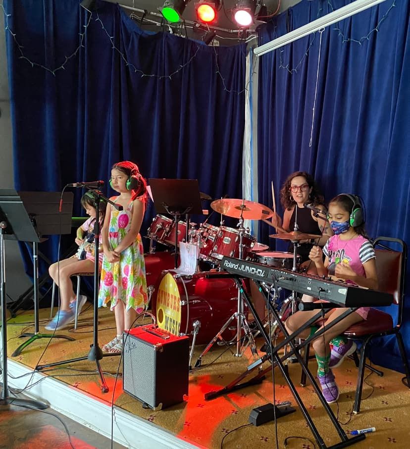 A group of young girls are singing and playing instruments on a stage.