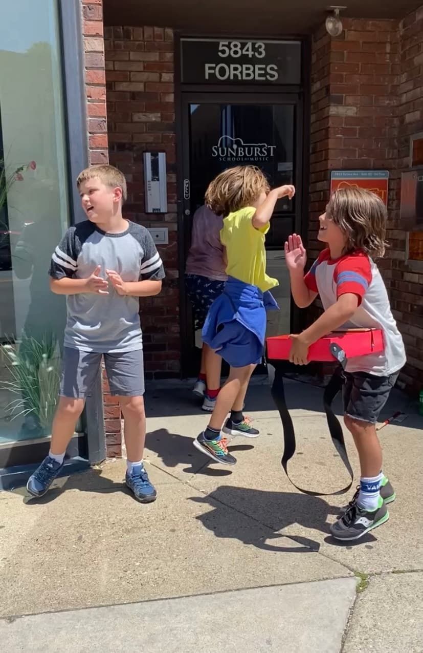 A group of young boys are standing on a sidewalk in front of a building.