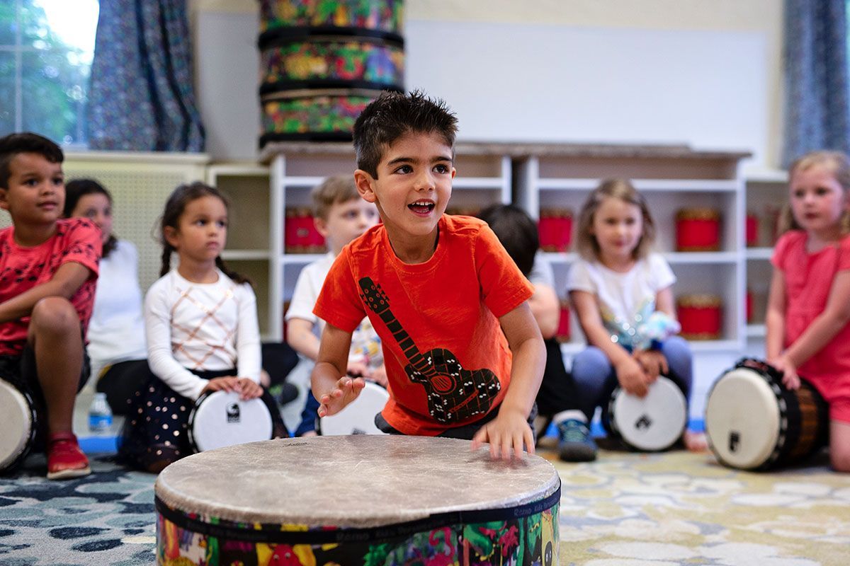 A group of children are playing drums in a classroom.