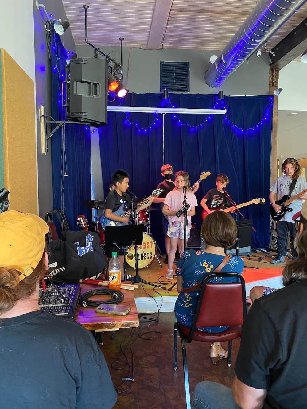 A group of people are sitting in front of a stage watching a band perform.