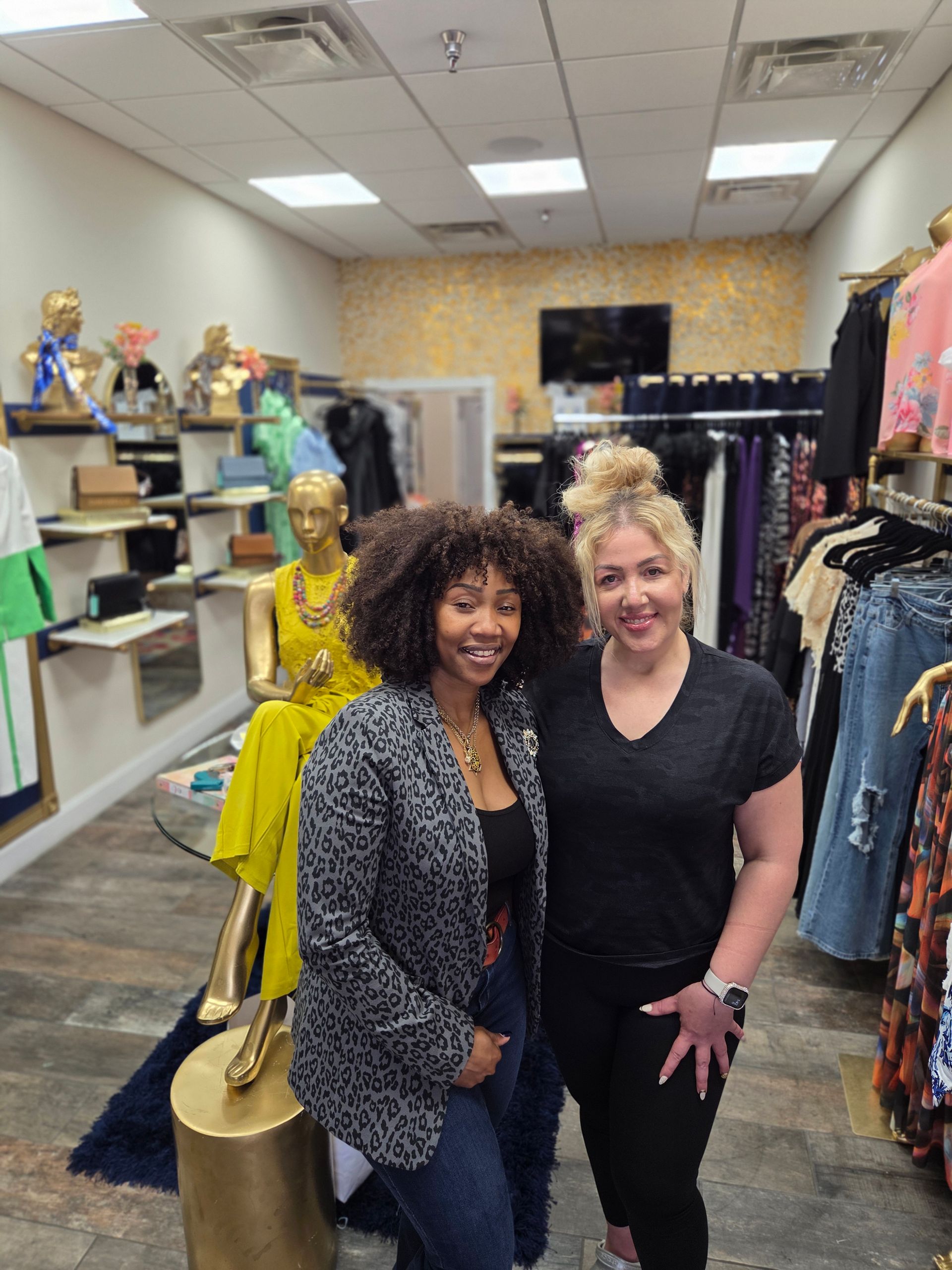 Two women smile in a clothing store. 