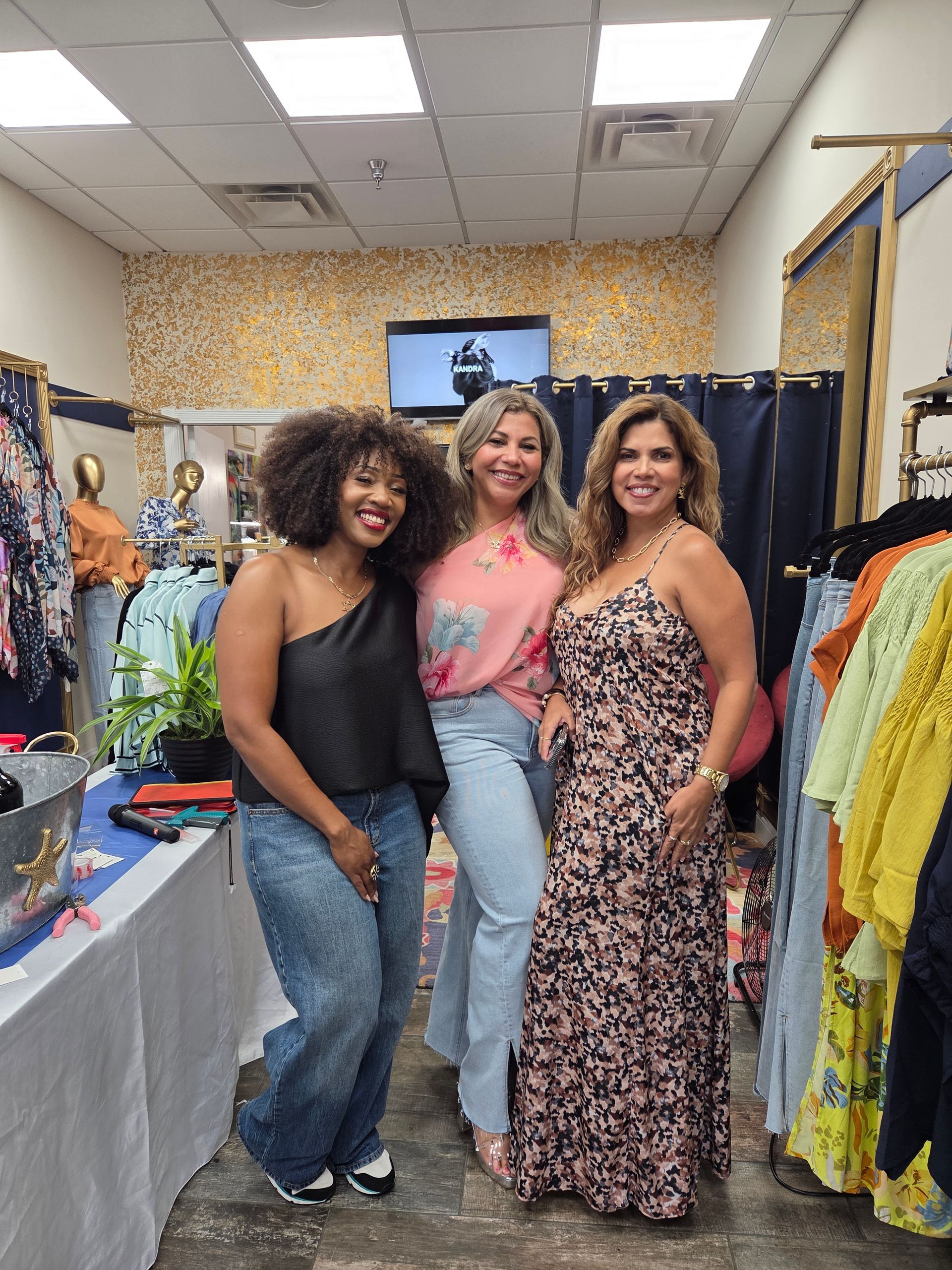 Exterior of a clothing boutique with mannequins in the window. Dark trim against brick building.