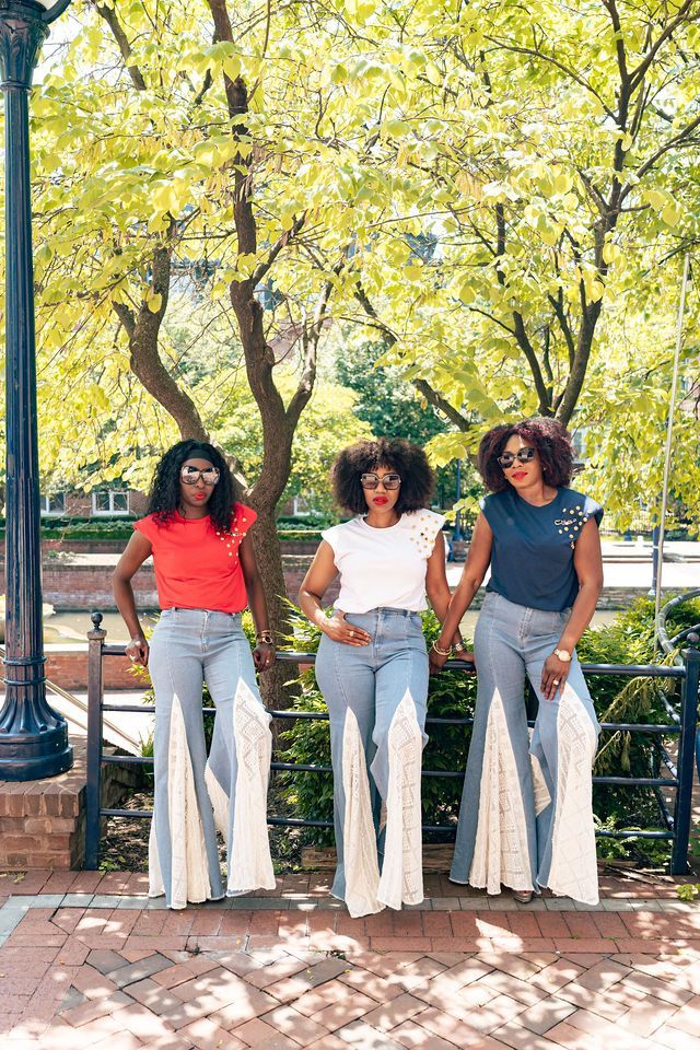 Three people standing outdoors wearing flare jeans with cream-colored panels and colorful tops.