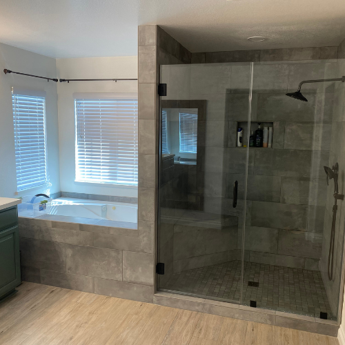 A bathroom with a tub and a shower with a glass door.
