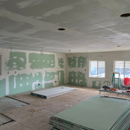 A large room with a stack of drywall sheets on the floor.