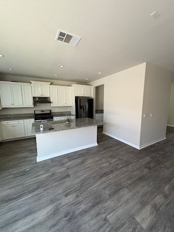 Modern kitchen with white cabinets, gray countertops, stainless steel appliances, and gray wood flooring.