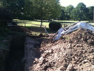 A bobcat excavator is digging a hole in the ground