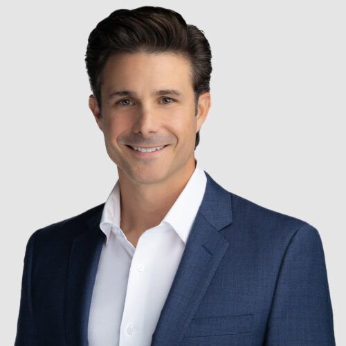 Man in a blue blazer and white shirt, smiling, looking at the camera.