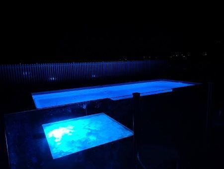 A Large House With A Swimming Pool In Front Of It — Pool Builder in Moore Creek, NSW
