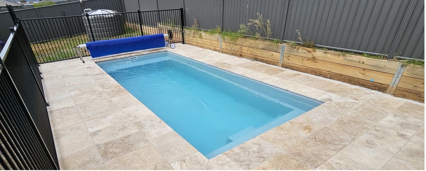 A Swimming Pool With A Blue Cover Rolling In The Pool — Pool Builder in Moore Creek, NSW