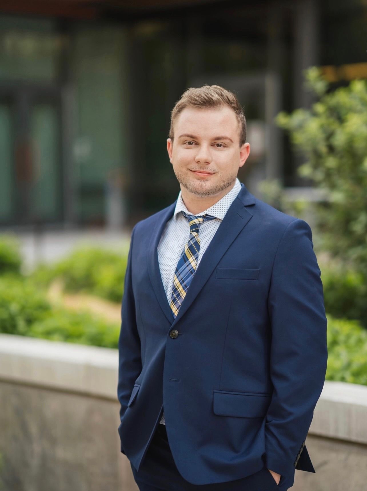 A man in a suit and tie is standing in front of a building.