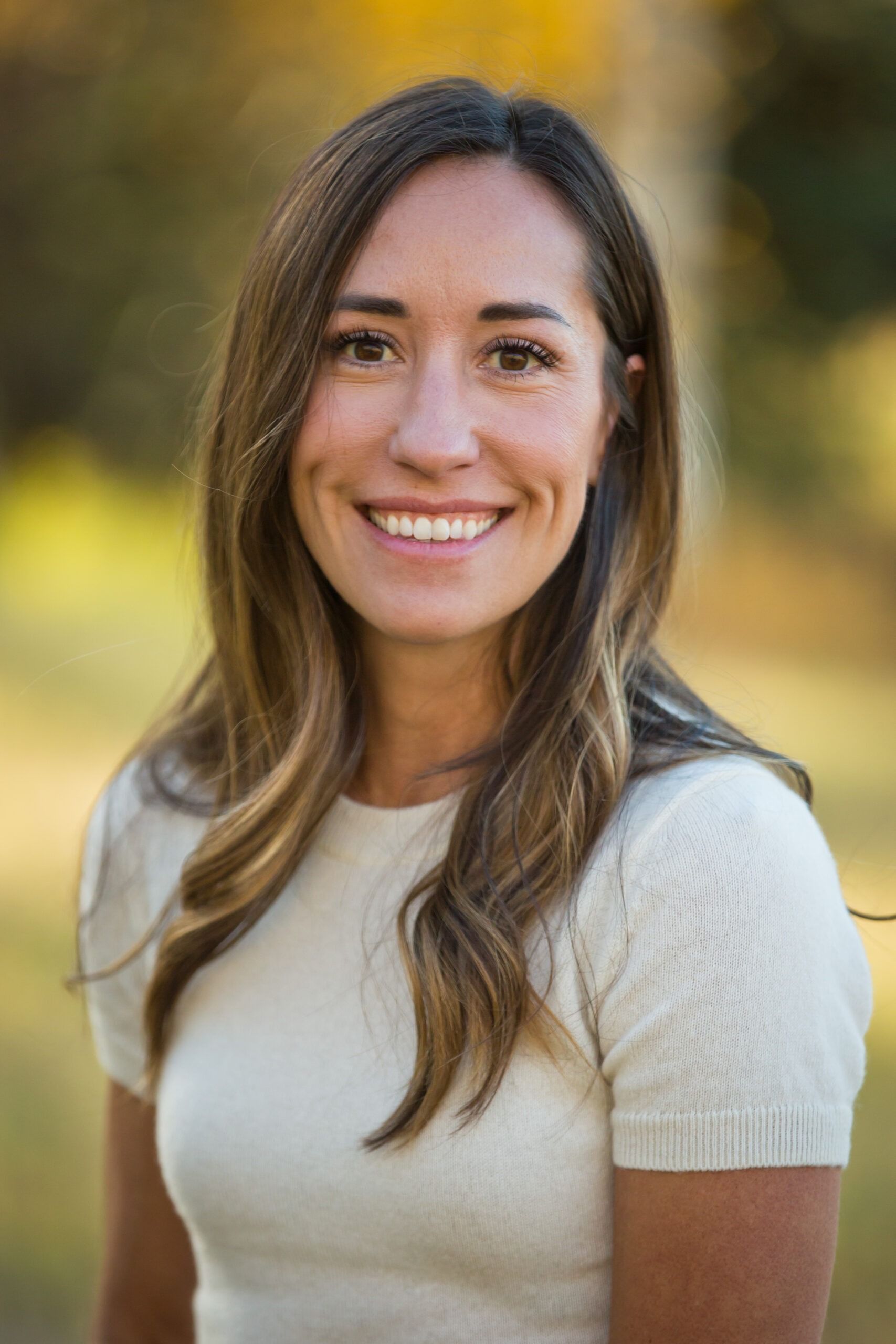 A woman in a white shirt is smiling for the camera.