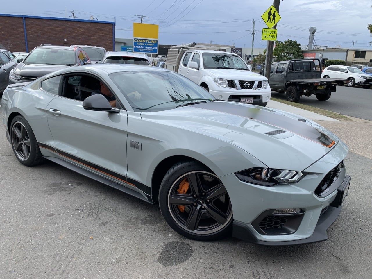 A gray ford mustang is parked in a parking lot.