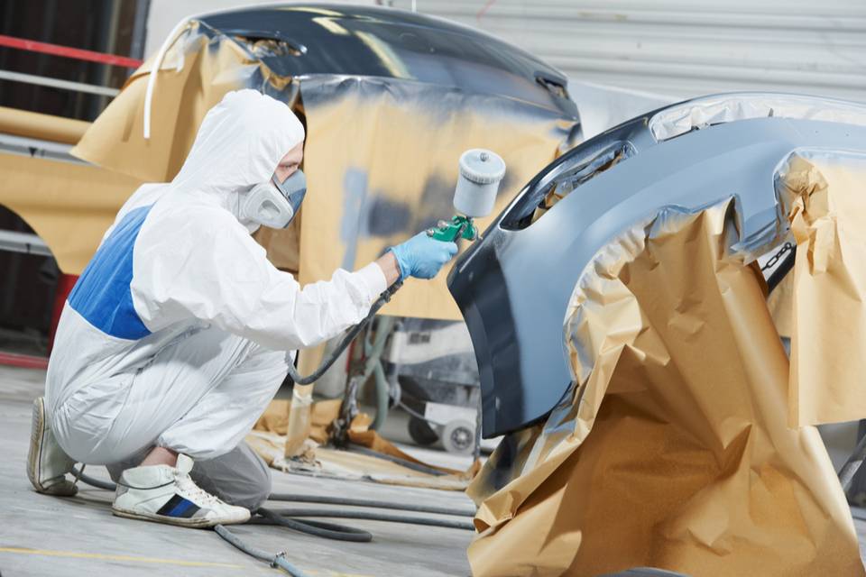 worker painting a car in a paint booth