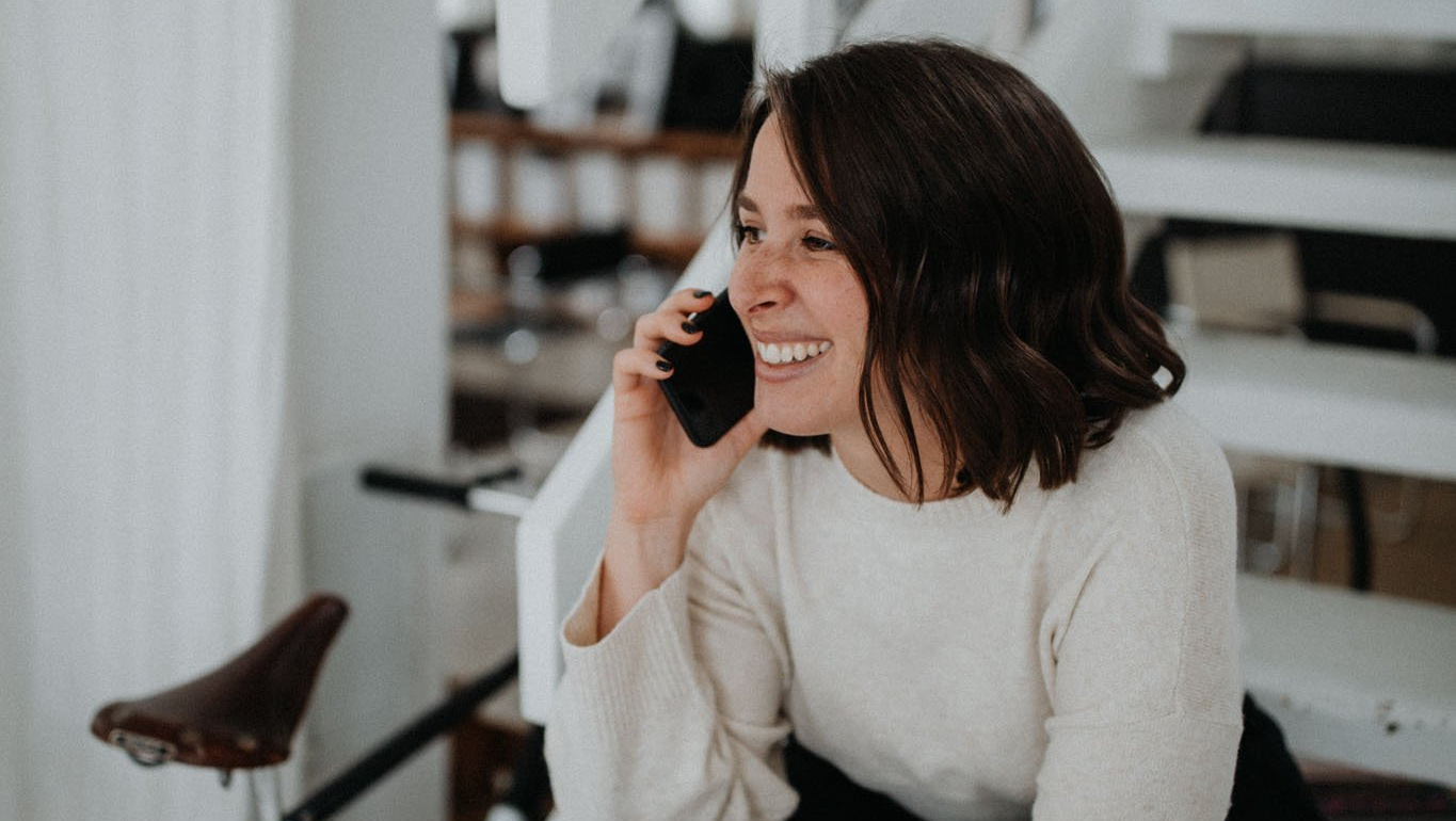 Eine Frau lächelt, während sie mit einem Mobiltelefon telefoniert.