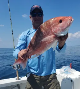 A man is holding a large red fish on a boat.